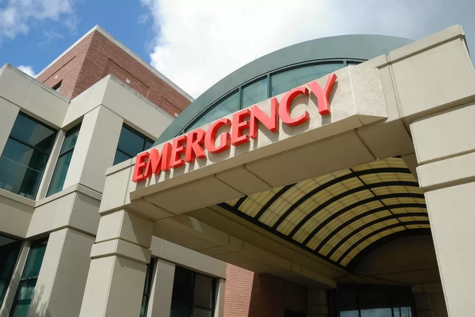Close-up of red EMERGENCY sign above hospital emergency room entrance.